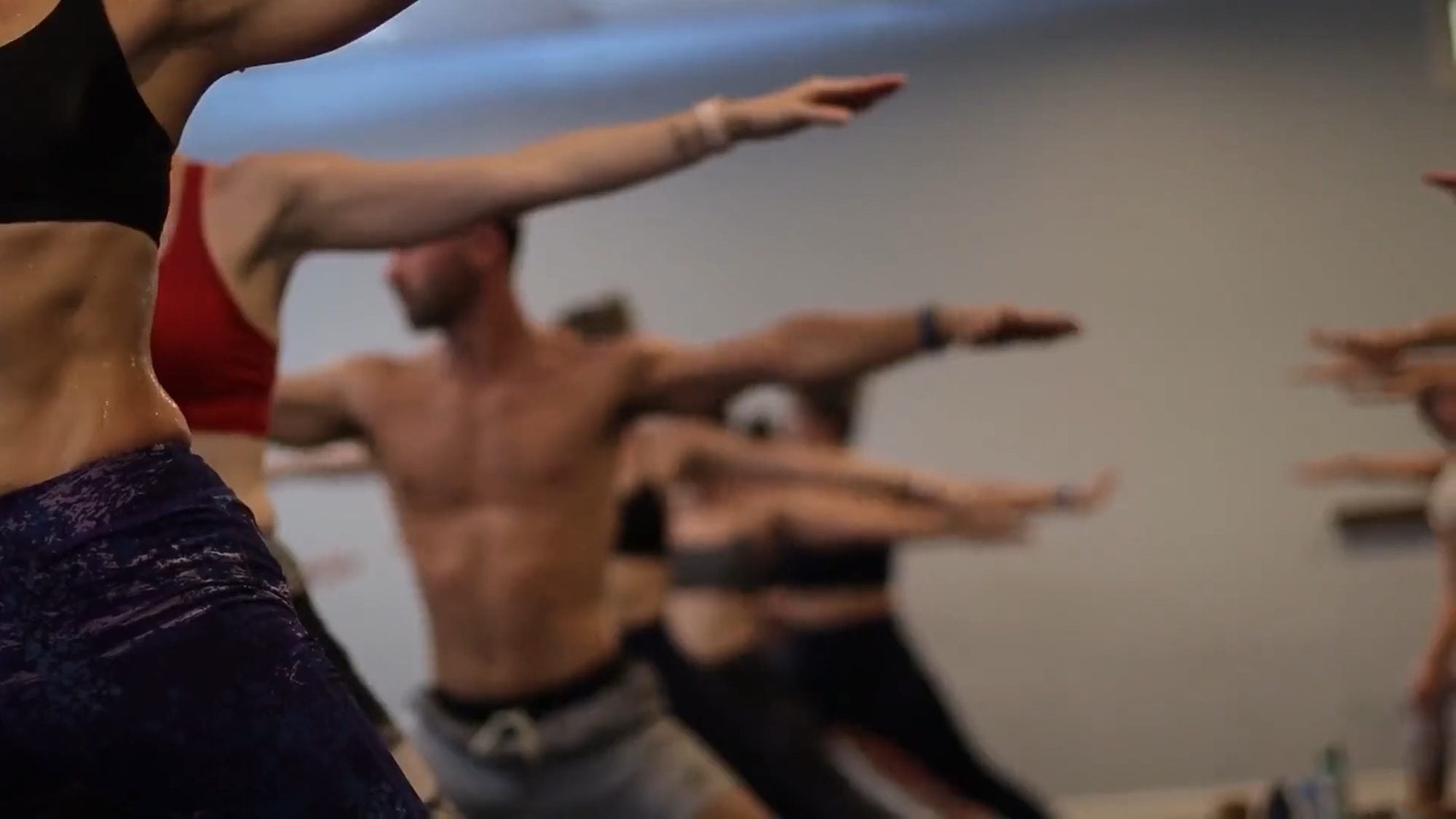 Arms stretched out in warrior pose, the nearest hand sharp and the room falling out of focus